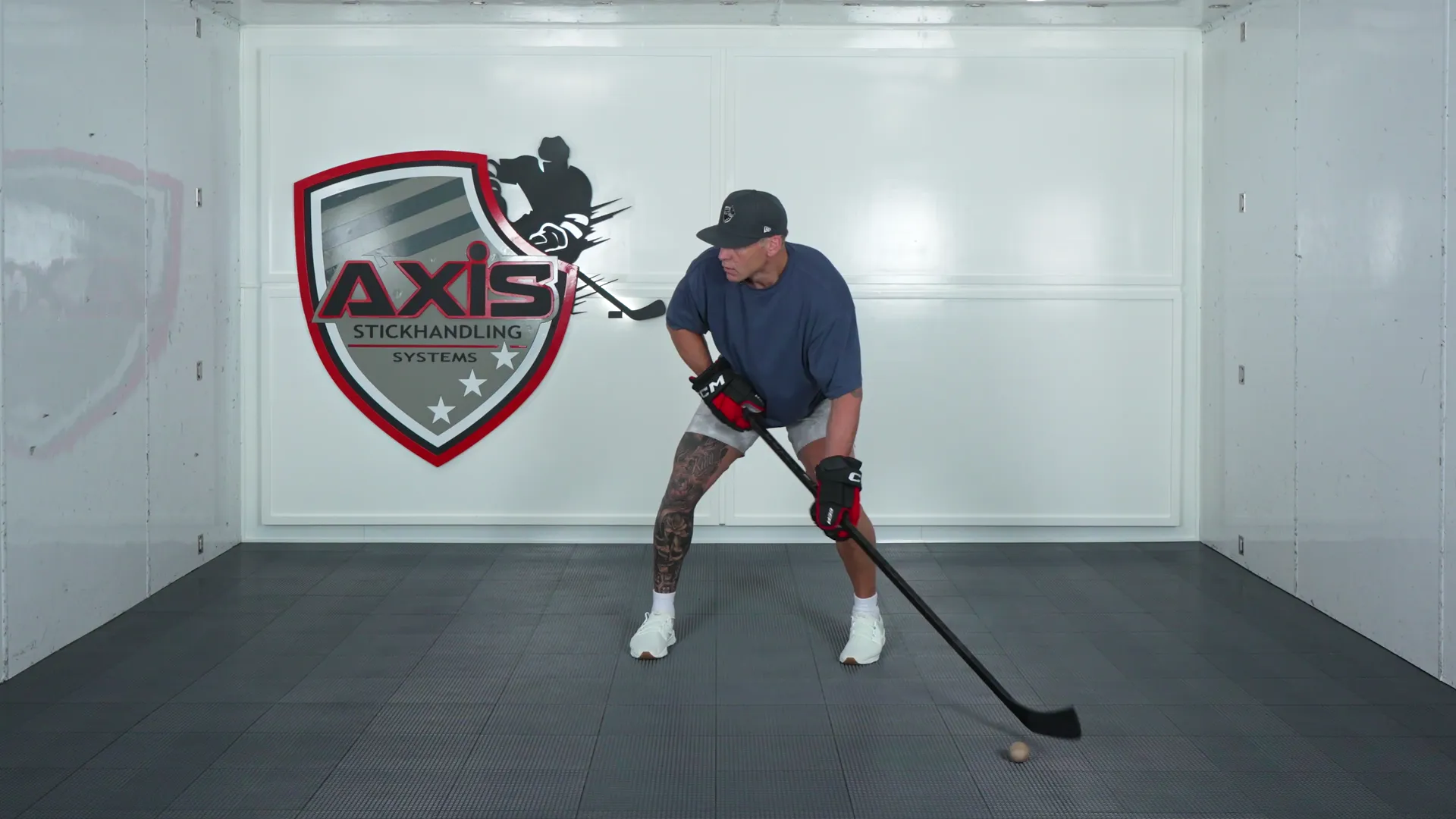 A coach reaching wide with the stick to move a ball across the body